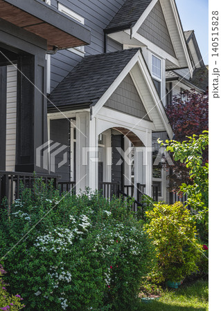 Luxury residential house with green grass lawn and plants in the garden. Real Estate Exterior Front House in a residential neighborhood. Home front yard on a sunny summer day. Cozy patio area. Nobody 140515828
