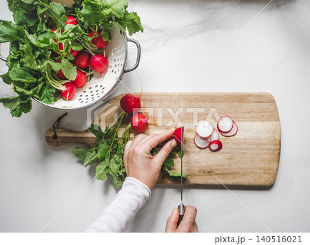 Hands slicing fresh red radishes Hands slicing fresh red radishes 140516021