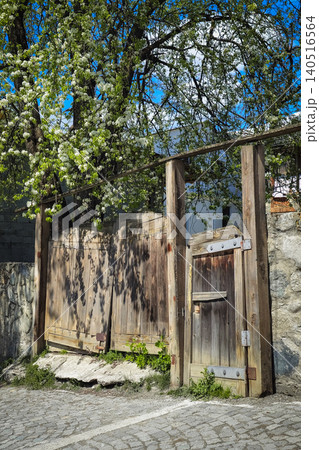 Weathered wooden gate stands beside cobblestone path 140516564