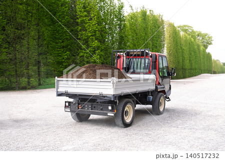Small dump truck carrying soil on rural gravel road with green forest background 140517232