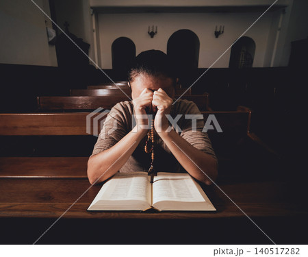 Christian woman praying in church. Hands crossed and Holy Bible on wooden desk. 140517282