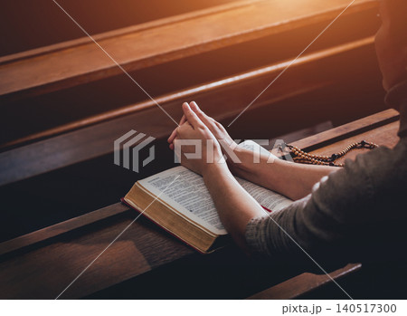 Christian woman praying in church. Hands crossed and Holy Bible on wooden desk. Christian woman praying in church. Hands crossed and Holy Bible on wooden desk. 140517300
