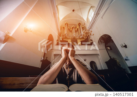 Christian woman praying in church. Hands crossed and Holy Bible on wooden desk. 140517301