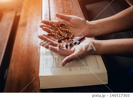 Christian woman praying in church. Hands crossed and Holy Bible on wooden desk. Christian woman praying in church. Hands crossed and Holy Bible on wooden desk. 140517303