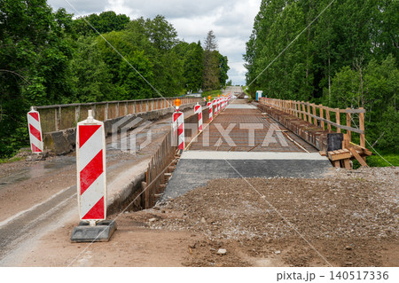Bridge reconstruction over the Barta River in Latvia with traffic barriers and repair works underway Bridge reconstruction over the Barta River in Latvia with traffic barriers and repair works underway 140517336