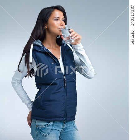 Woman, drink water for health and hydration in studio, nutrition and wellness with thirst on grey background. Liquid, aqua and mineral with h2o in glass, fresh and clean for refreshment and detox 140517387
