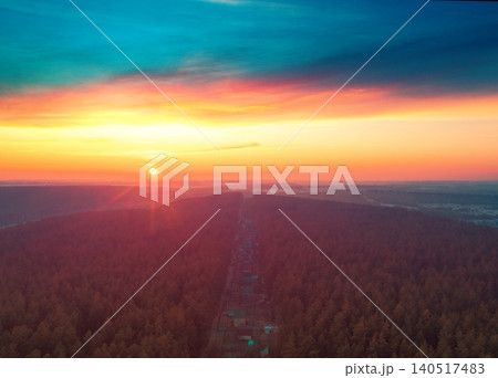Beautiful dramatic evening sky over pine forest. Village in the forest during sunset. Aerial view 140517483