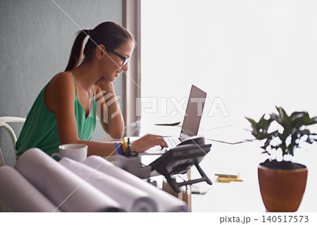 Business woman, reading and typing on laptop for planning, research and real estate website in her home office. Architecture worker, realtor or freelancer with computer for floor plan or blueprint 140517573