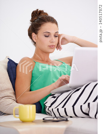 Student woman, laptop and working on couch busy, searching and concentration with computer in living room. Female person, casual outfit and coffee on sofa or lounge, online and connectivity in house 140517872