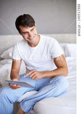 Man, happy and tablet in bedroom, scroll and entertainment in pajamas and morning routine. Male person, browse and social media with technology, bed and smile in sleepwear at home for relaxation Man, happy and tablet in bedroom, scroll and entertainment in pajamas and morning routine. Male person, browse and social media with technology, bed and smile in sleepwear at home for relaxation 140517988
