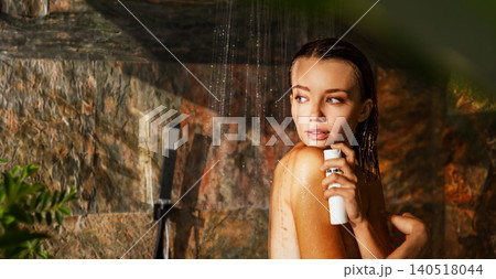 Caucasian young adult woman holding skincare bottle under running water in outdoor shower Caucasian young adult woman holding skincare bottle under running water in outdoor shower 140518044