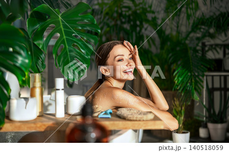 Happy young Caucasian woman smiling while relaxing in bathtub at bright home spa bathroom Happy young Caucasian woman smiling while relaxing in bathtub at bright home spa bathroom 140518059