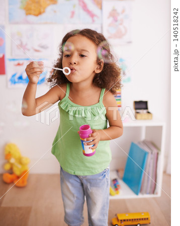Girl, toy and blowing bubbles for development, playing and having fun alone in room. Happiness, growth and face of young child in kindergarten for learning, soap bubble wand and activity games Girl, toy and blowing bubbles for development, playing and having fun alone in room. Happiness, growth and face of young child in kindergarten for learning, soap bubble wand and activity games 140518242