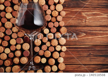 Red wine pouring in a glass standing on corks 140518508