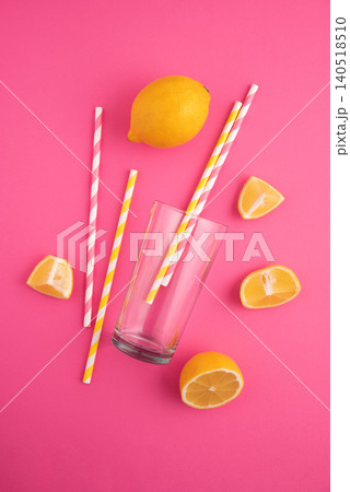 Lemons, glass, and paper straws inviting refreshing drink on pink background Lemons, glass, and paper straws inviting refreshing drink on pink background 140518510