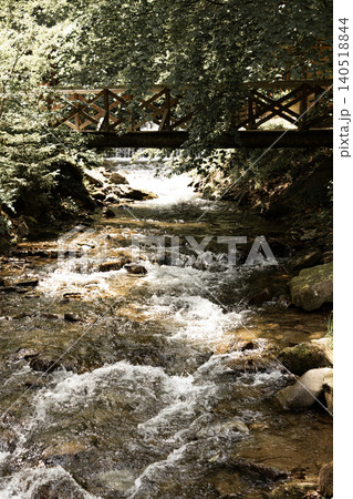 Wooden bridge over rocky mountain stream in forest Wooden bridge over rocky mountain stream in forest 140518844
