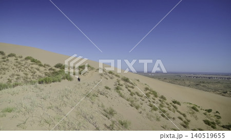 Panoramic Aerial Scene Showcasing Hikers Traversing Golden Sand Dunes Beneath Clear Blue Sky. Stock Clip Panoramic Aerial Scene Showcasing Hikers Traversing Golden Sand Dunes Beneath Clear Blue Sky. Stock Clip 140519655