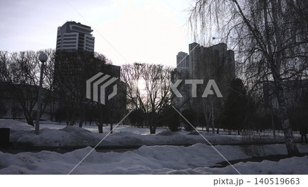 Evening City Park Quiet Scene. Lone Individual Traverses Snowblanketed City Park During Twilight . Media Evening City Park Quiet Scene. Lone Individual Traverses Snowblanketed City Park During Twilight . Media 140519663