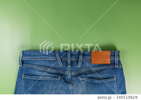 Closeup of denim jeans on a green surface with pockets and seams visible Closeup of denim jeans on a green surface with pockets and seams visible 140519829