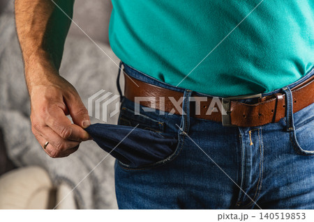 Man checks empty pocket for cash while wearing jeans and belt Man checks empty pocket for cash while wearing jeans and belt 140519853