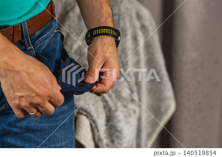 Man checking empty pocket in jeans while standing indoors Man checking empty pocket in jeans while standing indoors 140519854