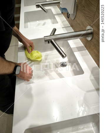 Cleaning the sink in a public restroom Cleaning the sink in a public restroom 140520225