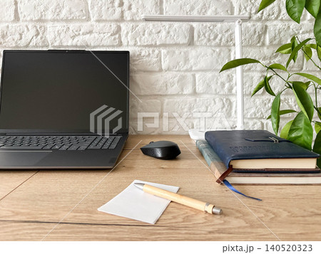 a minimalist workspace with laptop arranged on a light wooden desk against a textured white brick wall. a minimalist workspace with laptop arranged on a light wooden desk against a textured white brick wall. 140520323