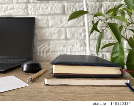 a serene and organized workspace set upon a light wooden desk against a backdrop of a white painted brick wall. a serene and organized workspace set upon a light wooden desk against a backdrop of a white painted brick wall. 140520324