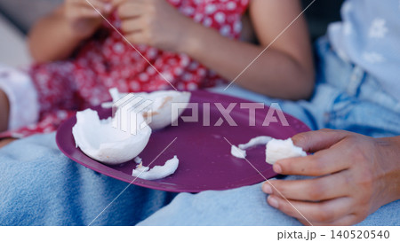 Family members hands sharing fresh coconut pieces on a plate 140520540