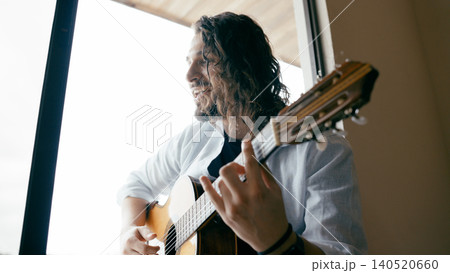 Man playing acoustic guitar and smiling indoors Man playing acoustic guitar and smiling indoors 140520660