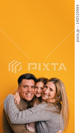 Happy family hugging and posing on yellow background 140520984