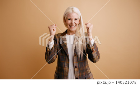 Happy mature woman celebrating achievement with raised fists 140521078