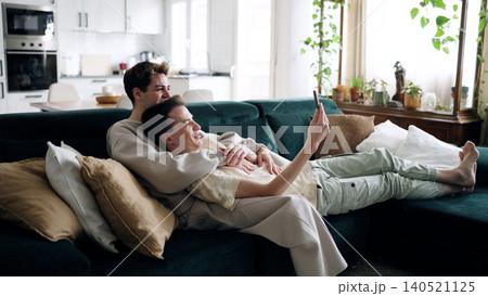 Gay couple relaxing on couch using smartphone Gay couple relaxing on couch using smartphone 140521125