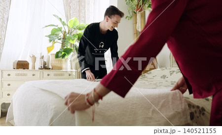 Gay couple making bed together in morning bedroom 140521155