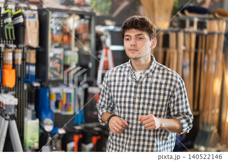 In hardware store department, young man looking for something on shelf of showcase In hardware store department, young man looking for something on shelf of showcase 140522146
