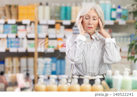 Mature woman with headache in pharmacy Mature woman with headache in pharmacy 140522241
