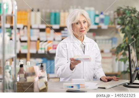 Female pharmacist working at computer offering pills 140522325