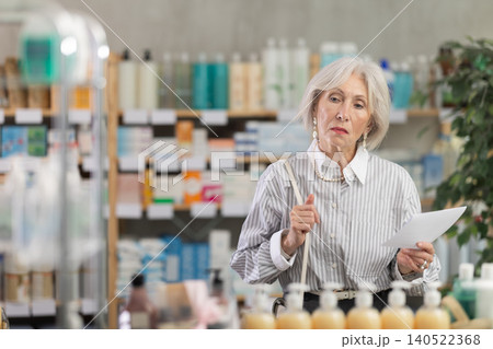 Elderly woman chooses prescription pills at pharmacy Elderly woman chooses prescription pills at pharmacy 140522368