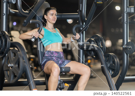 Woman using chest press machine during workout at gym Woman using chest press machine during workout at gym 140522561
