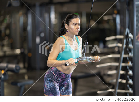 In gym, woman uses cable row machine to strengthen muscles. In gym, woman uses cable row machine to strengthen muscles. 140522620
