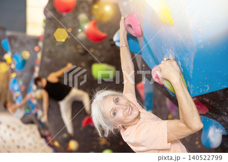Joyful concentrated senior woman busy with her hobby bouldering, climbing on artificial wall in gym, extreme sport, rock-climbing concept Joyful concentrated senior woman busy with her hobby bouldering, climbing on artificial wall in gym, extreme sport, rock-climbing concept 140522799