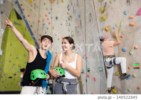 Motivated sporty young people, man and woman standing with special equipment before climbing up bouldering wall in amusement center 140522845
