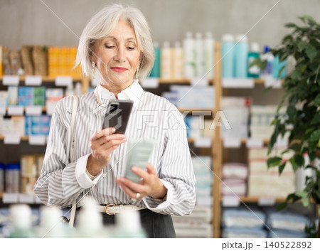 Elderly woman scanning qr code of cream Elderly woman scanning qr code of cream 140522892