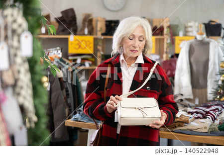Mature woman standing and choosing handbag on Christmas tree background 140522948
