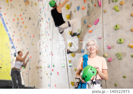 Senior confident female climber with her equipment getting ready for training Senior confident female climber with her equipment getting ready for training 140522973