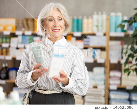 Elderly female pensioner in summer clothes choosing skin cream at drugstore 140523096
