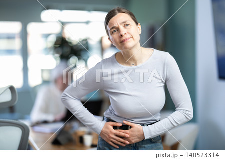 Female office worker suffers from abdominal pain Female office worker suffers from abdominal pain 140523314