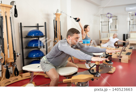 Adult man stretching her arms using pilates machine Adult man stretching her arms using pilates machine 140523663