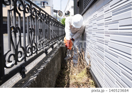 個人宅の敷地内に除草剤をまく作業員 140523684