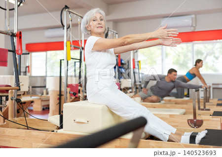 Senior woman performs exercise on reformer to improve coordination, balance, and posture 140523693